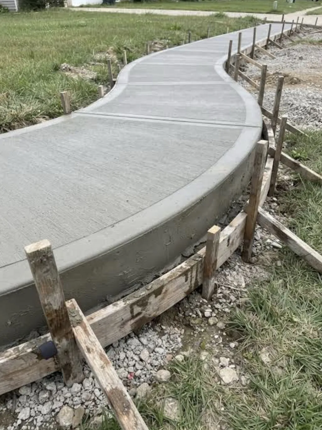 Freshly poured curved concrete walkway in wood forms