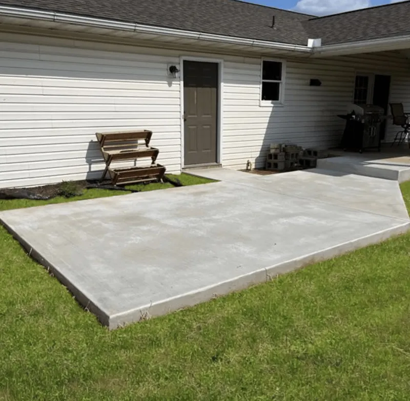 Finished light-gray concrete patio extending from a covered porch