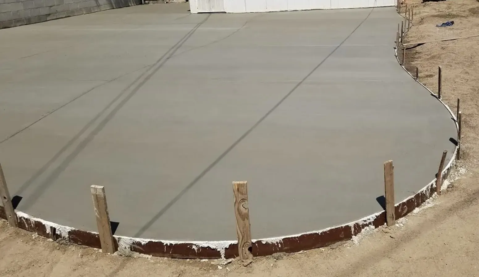 Freshly poured backyard concrete slab inside steel edge forms