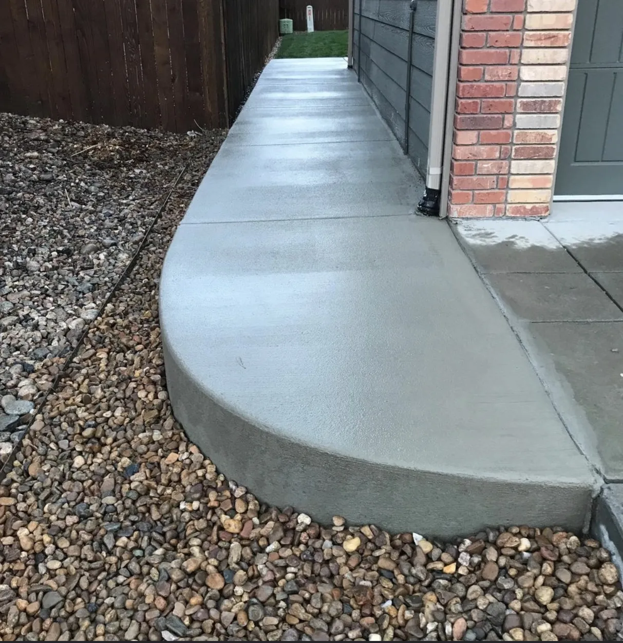 Finished concrete walkway with a rounded end along the side of a house